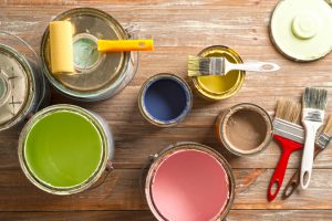 Paint cans, paint roller, and brushes on the old wooden background.